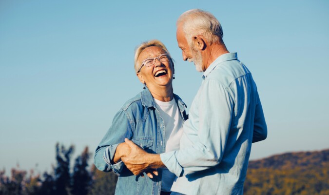 A couple smiling and dancing outside