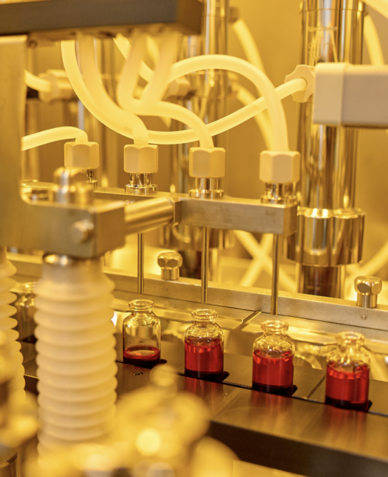 A machine filling vials up with a red liquid