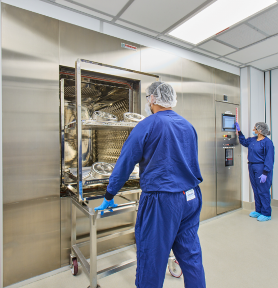 A worker in a blue clean suit using a machine