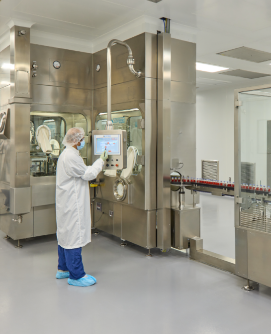 A worker in a white clean suit using a machine