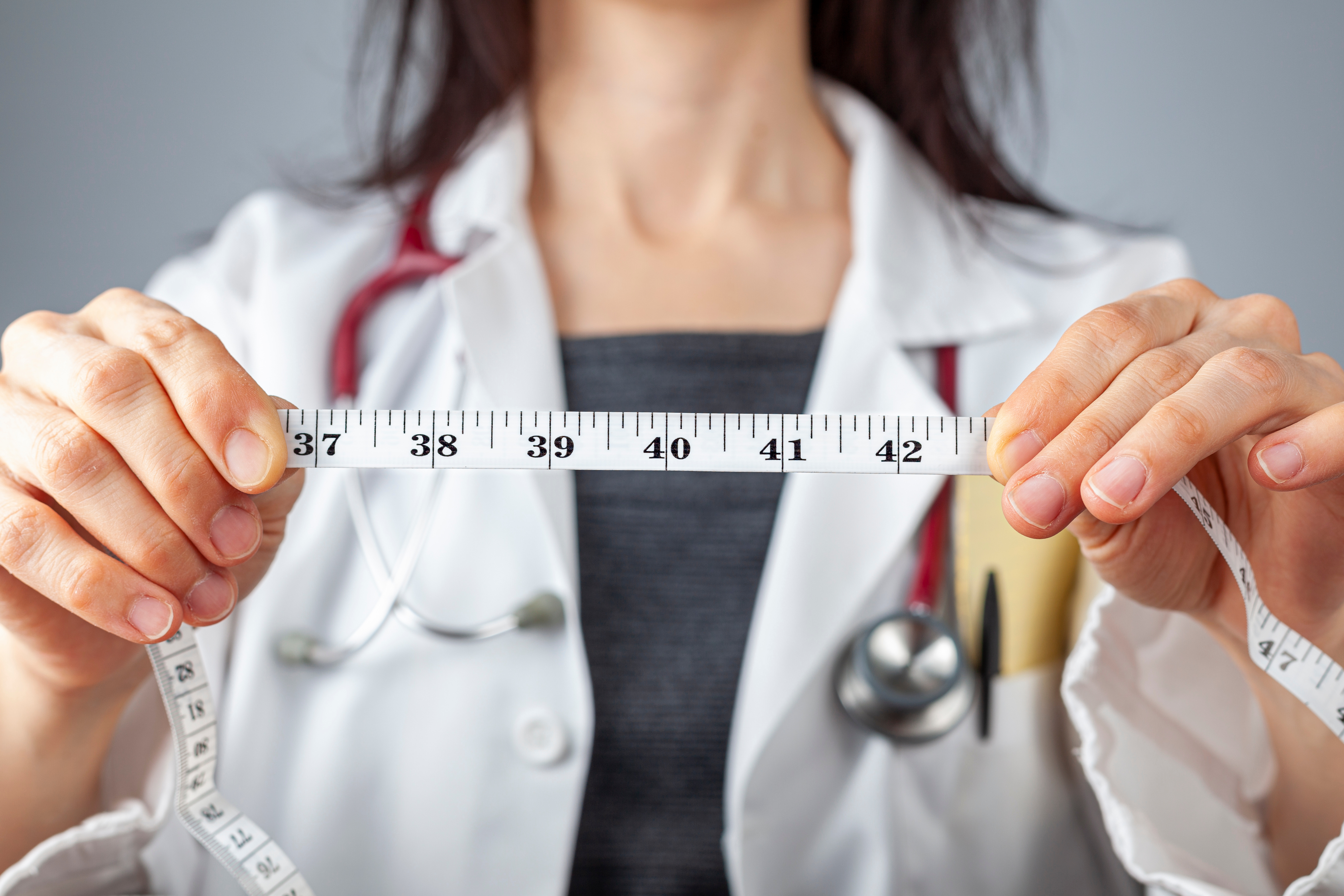 Doctor holding a tape measure in front of her.